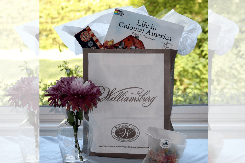 Flowers in a vase in front of a window over looking a year, with a gift back holding a child's coloring book, and candy.
