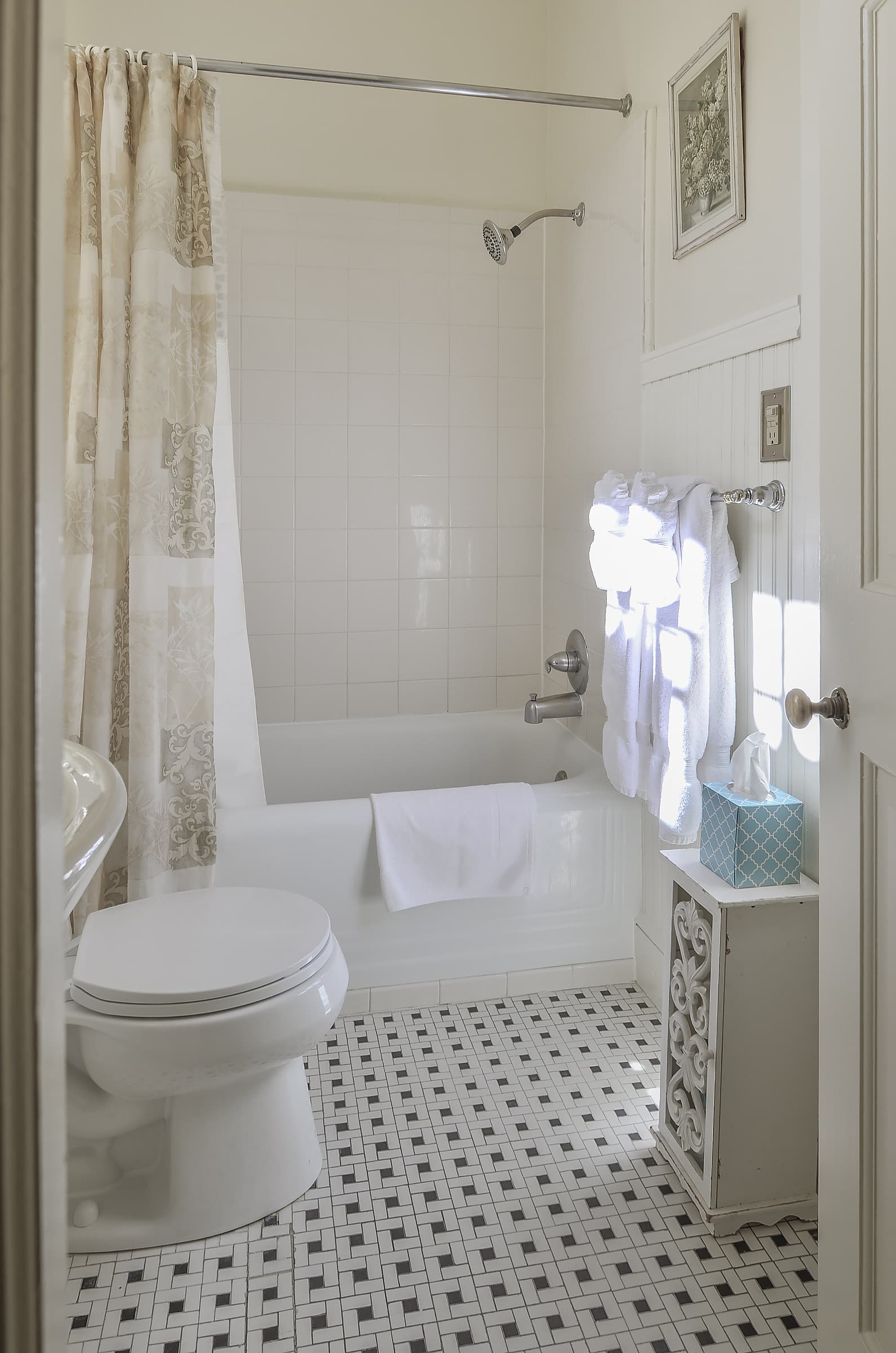 Bathroom with white tub and toilet and small decorative black and white floor tiles