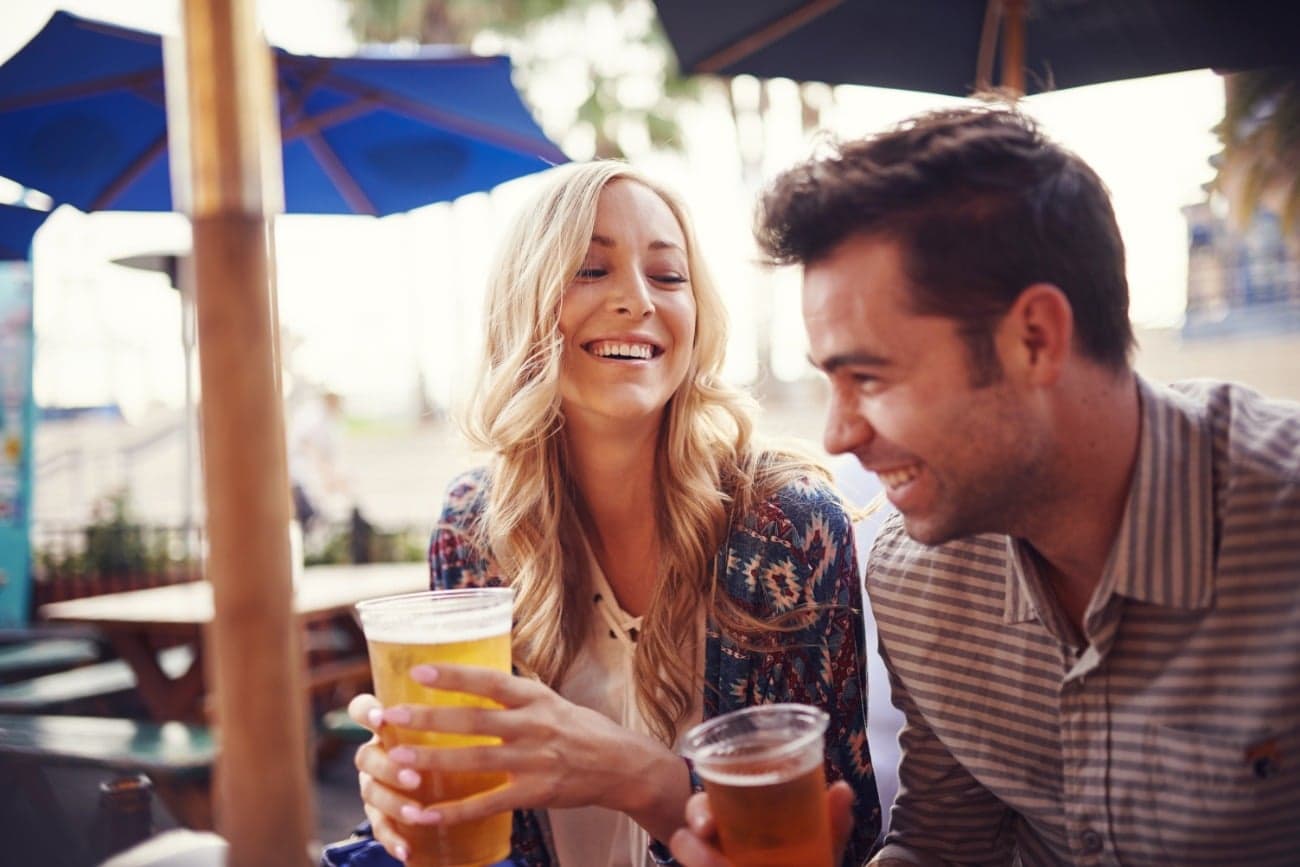 woman and man smiling holding beer outside on patio