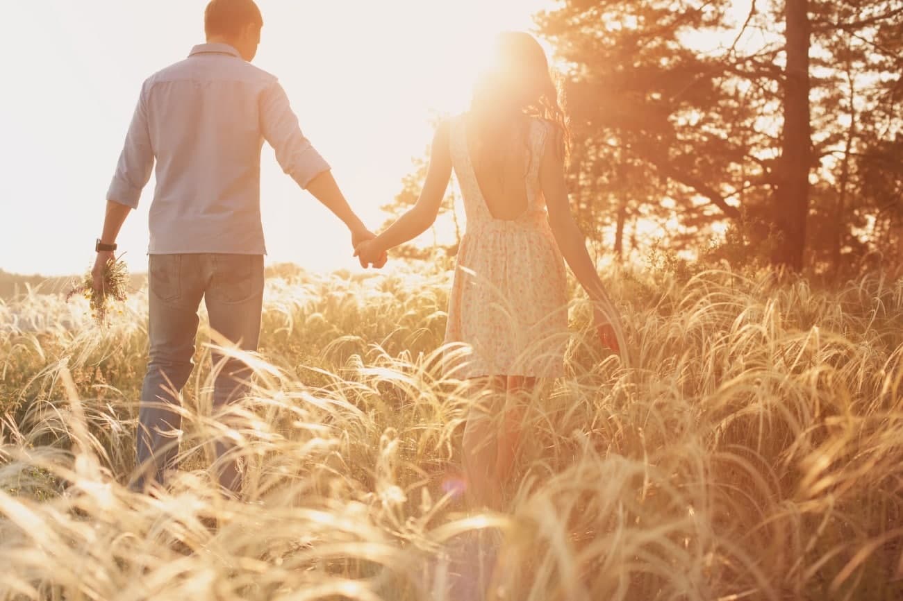 Couple walking through field, sun rays