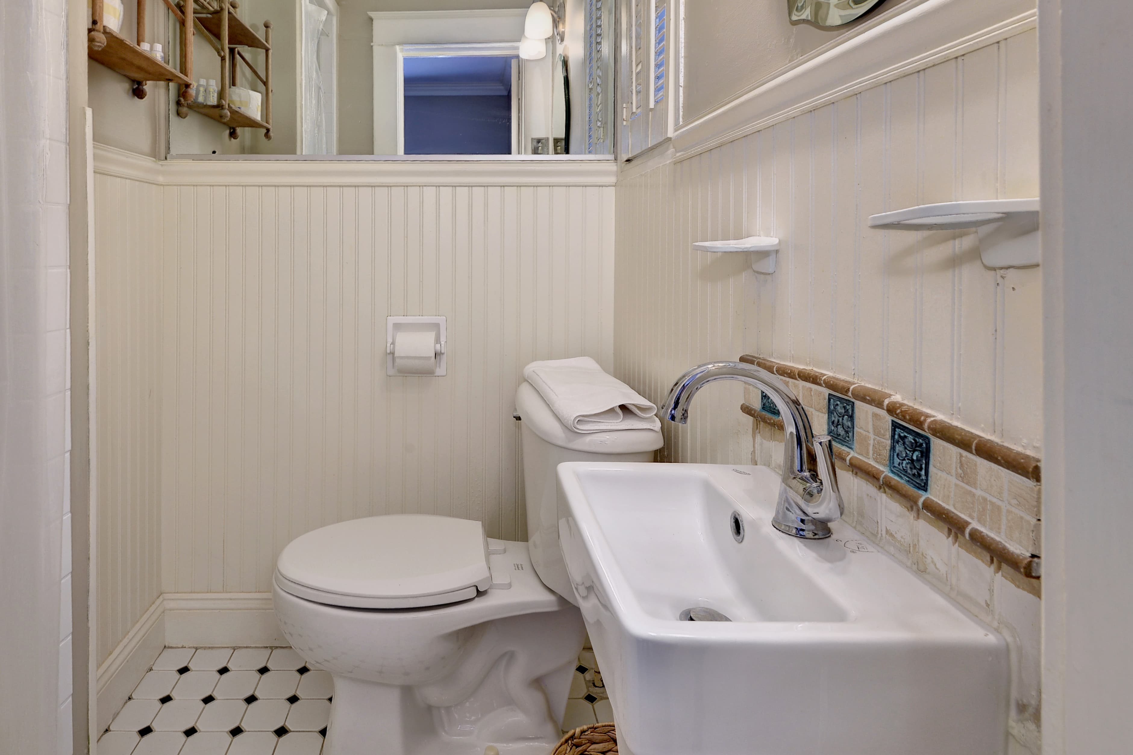 Bathroom with green walls, towels on rack, and a black and white tiled walk in shower