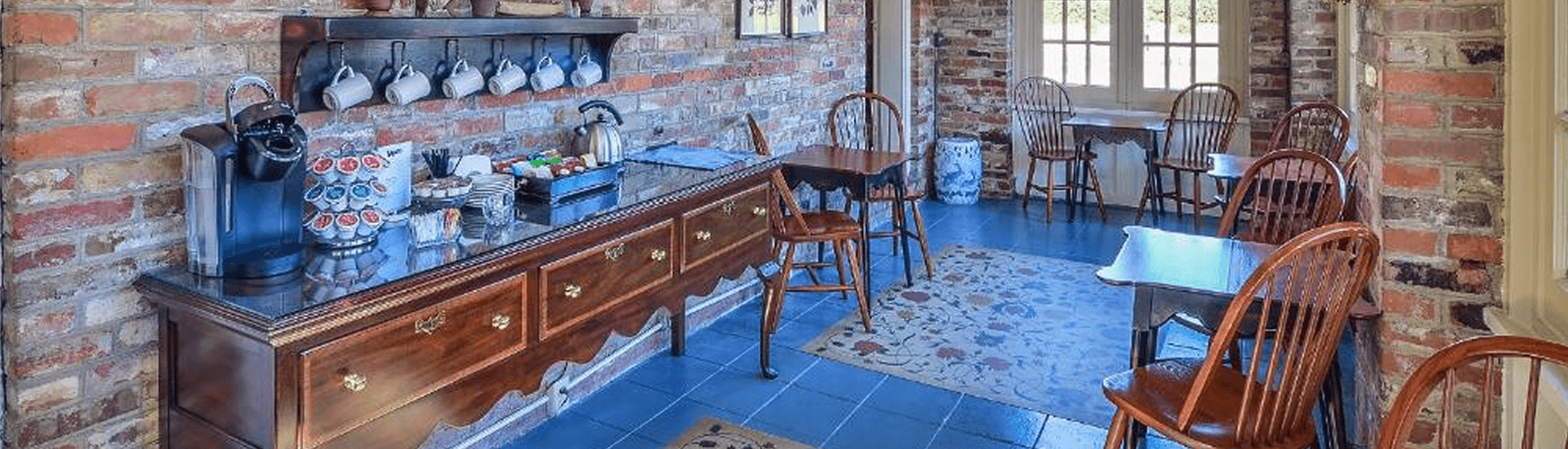 Brick walled buffet serving area for drinks and breakfast with wood tables and chairs