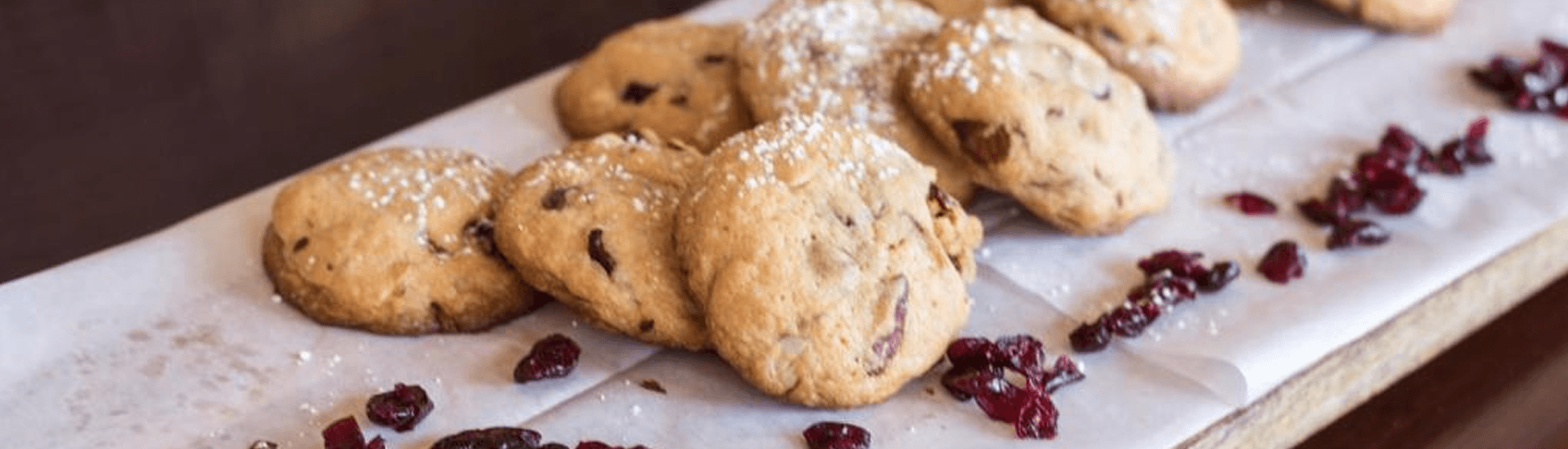 Rectangle plate of cookies on a white linen cloth with dried cranberries strewn on it